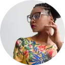 A stylish woman wearing sunglasses and a vibrant floral top, showcasing confidence and fashion, with a blurred city background. Perfect for fashion or lifestyle branding.