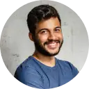 A smiling man with dark hair and a beard, wearing a blue shirt, representing the innovative TrueNumber platform for digital identity verification.