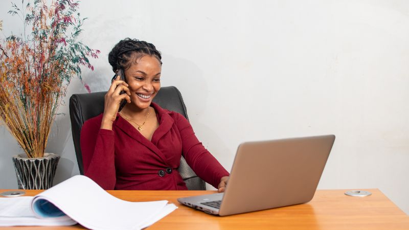 Smart woman talking on the phone with a laptop on desk for number validation.