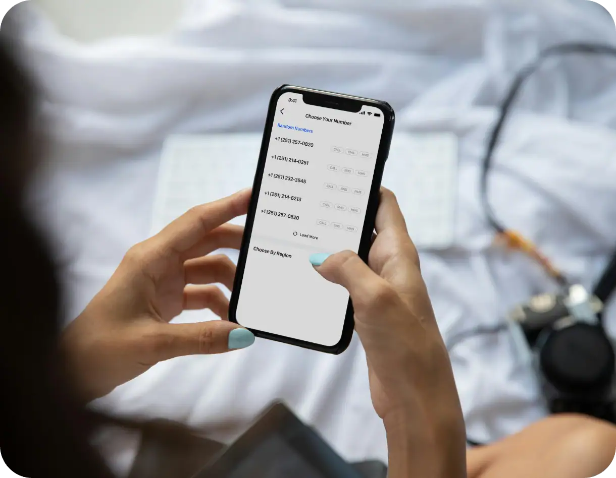A person holding an iPhone displaying a number selection app for generating and choosing phone numbers, ideal for privacy and business purposes, within a casual setting.