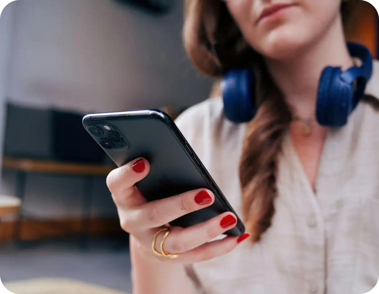 Close-up of a woman using a smartphone with focus on her hand and device, highlighting mobile number verification and TrueNumber's digital identification solutions for business and personal security.