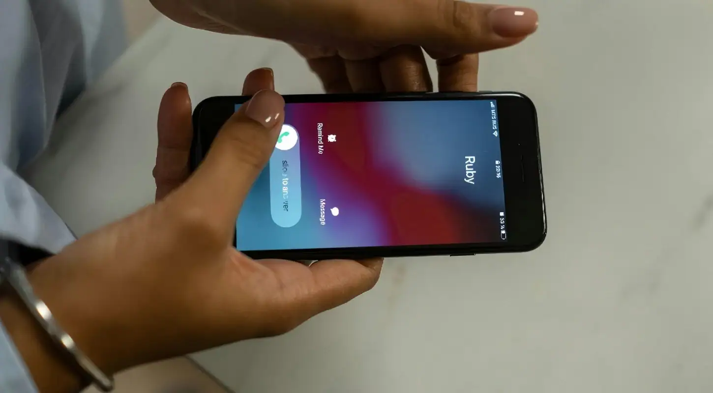 Person holding iPhone displaying TrueNumber app for adding a second phone number to your iPhone.