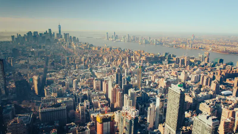 Aerial view of New York City skyline showing tall skyscrapers and the Hudson River on a clear day.